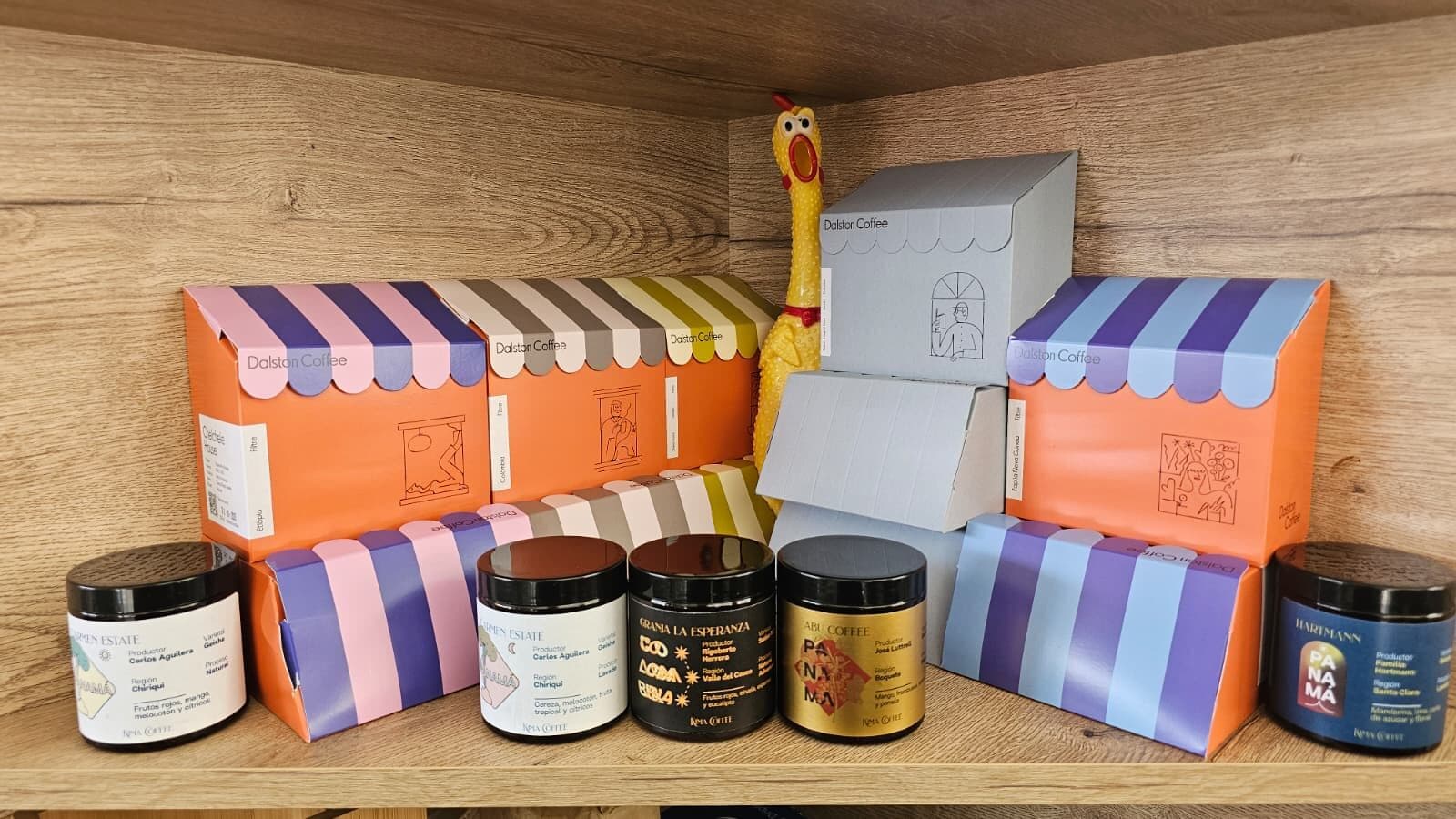 Cajas y tarros de café de especialidad de distintos orígenes colocados en la estantería